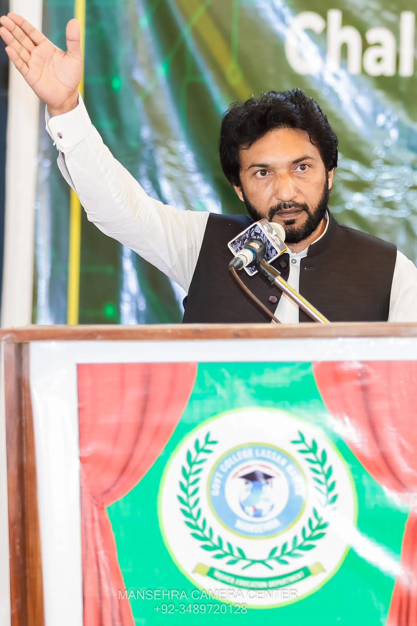 Qaiser Akash speaking at a podium during an event.