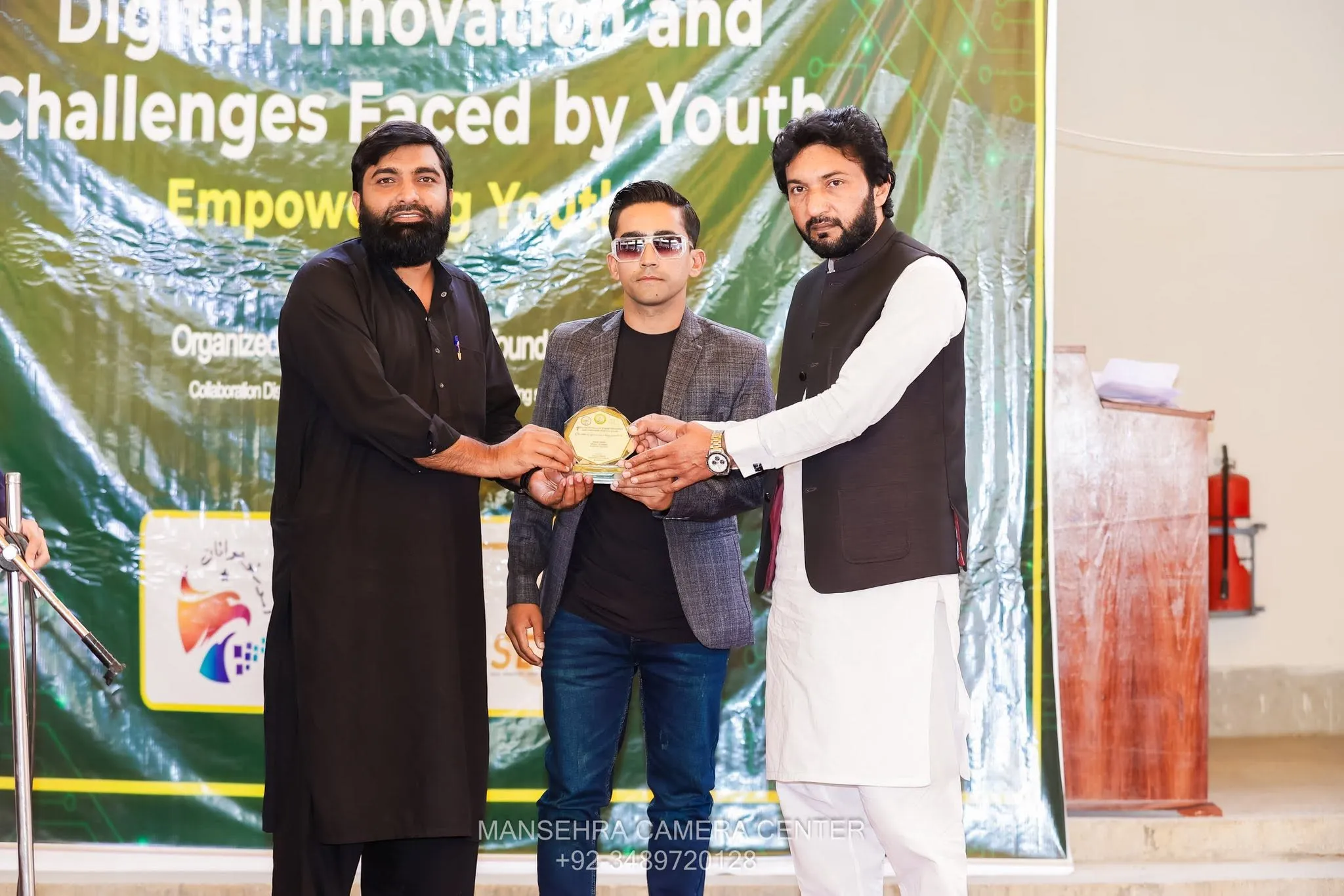 Qaiser Akash Khan presenting a shield award to a speaker in front of a Digital Innovation banner.