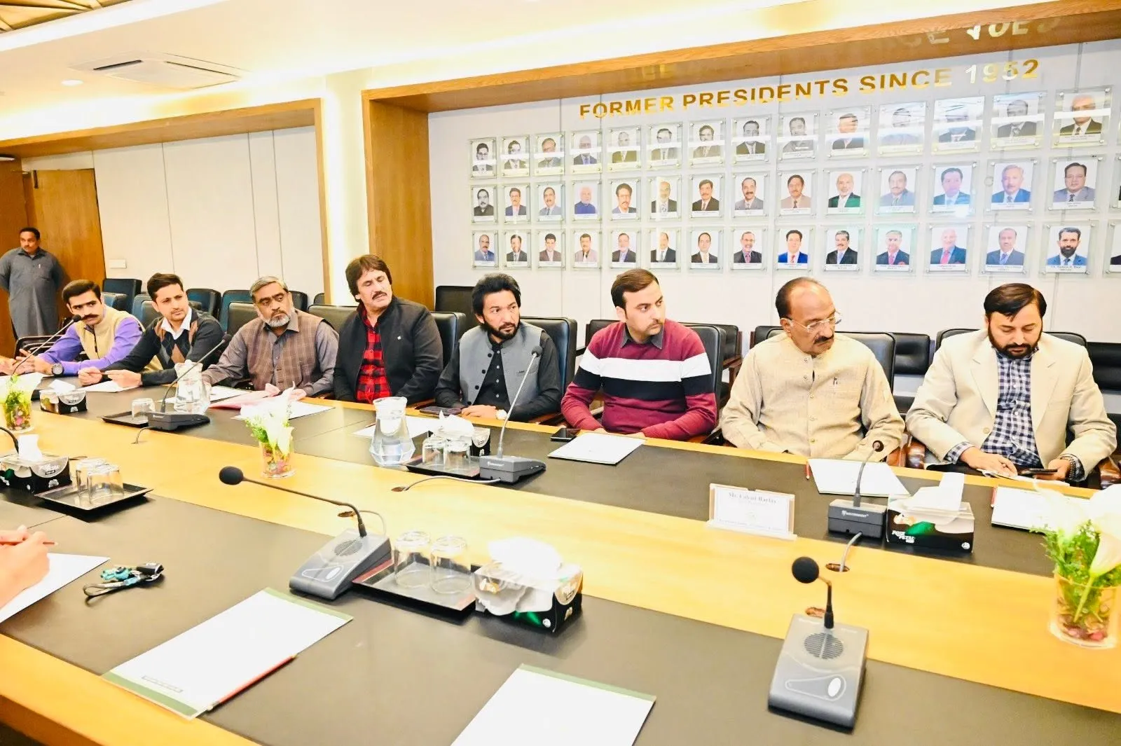 A group of people attending an official indoor meeting and presentation event.
