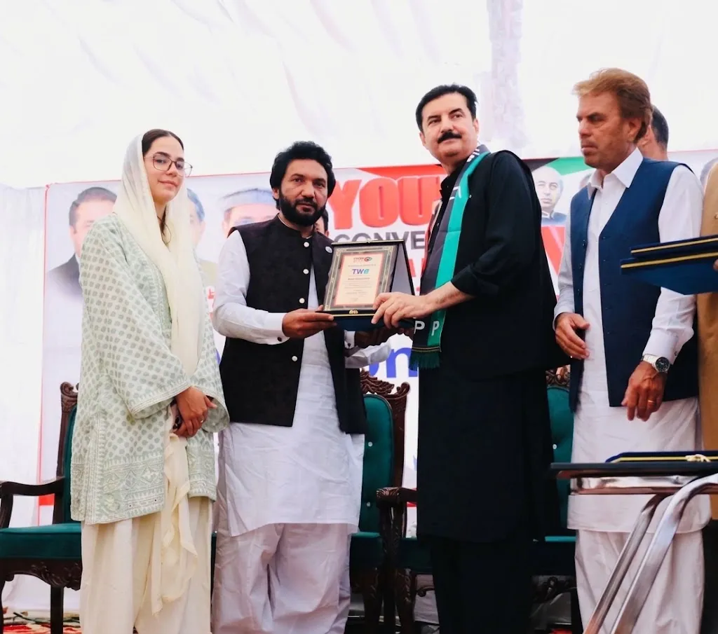 Governor of KP Faisal Karim Kundi presenting the Outstanding Humanitarian Services Award to the recipient on stage.