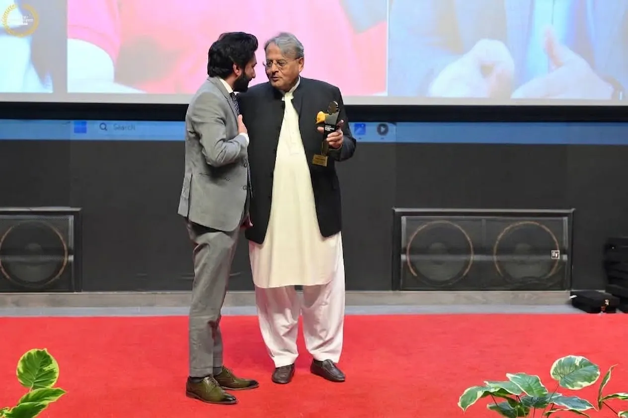 Three men on stage holding a trophy at the Pakistan Entrepreneur Awards ceremony, featuring Qaiser Akash Khan